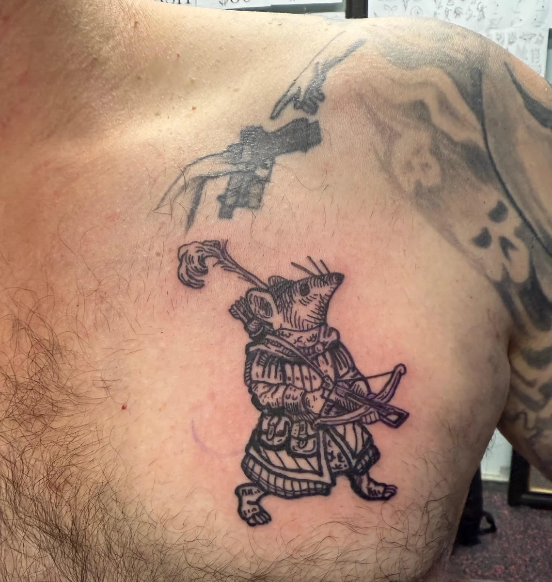 Illustrative mouse warrior tattoo on chest.