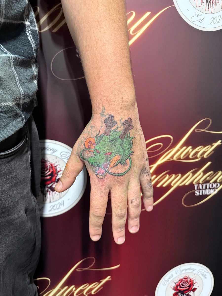 Colorful dragon tattoo on a hand.