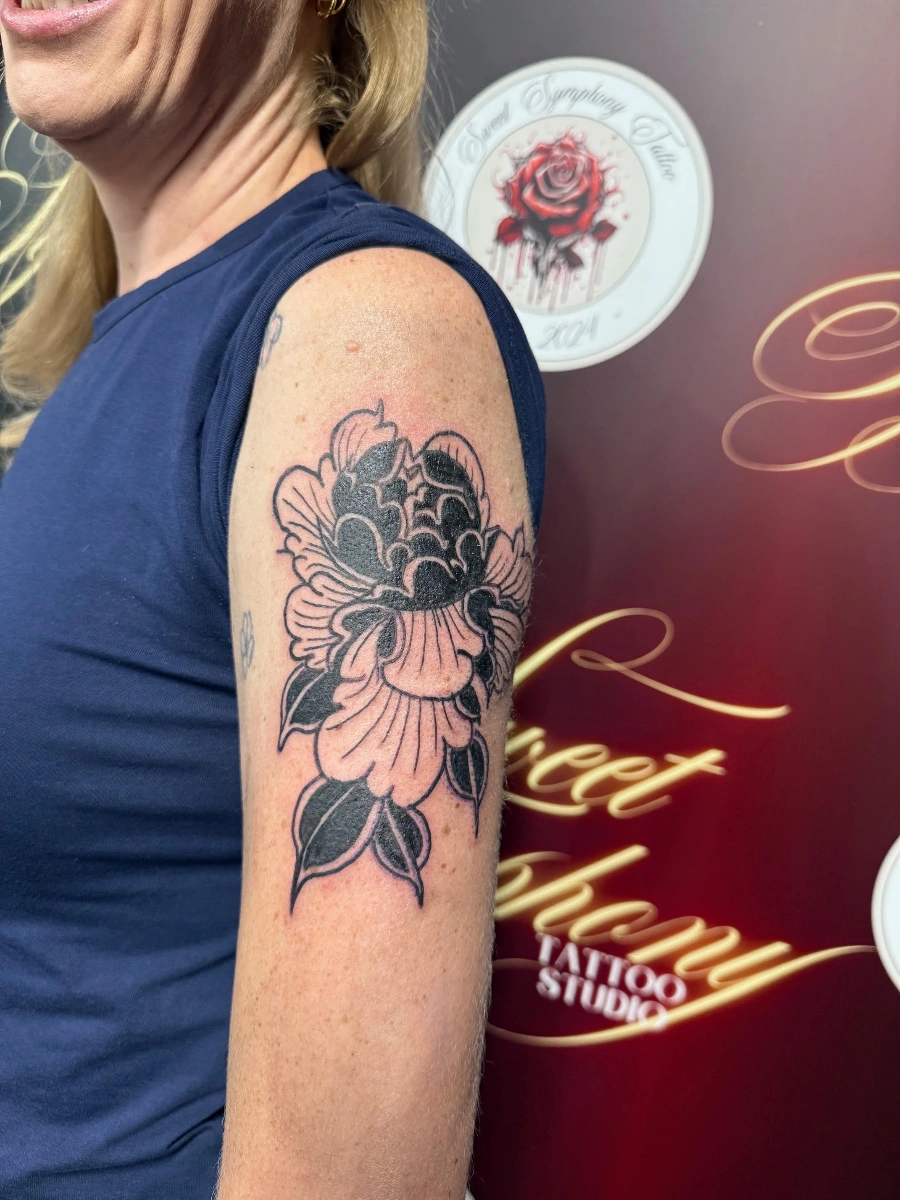 Black-and-grey peony tattoo on woman's arm.