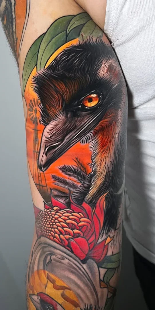 Vibrant bird tattoo on the arm with floral elements.