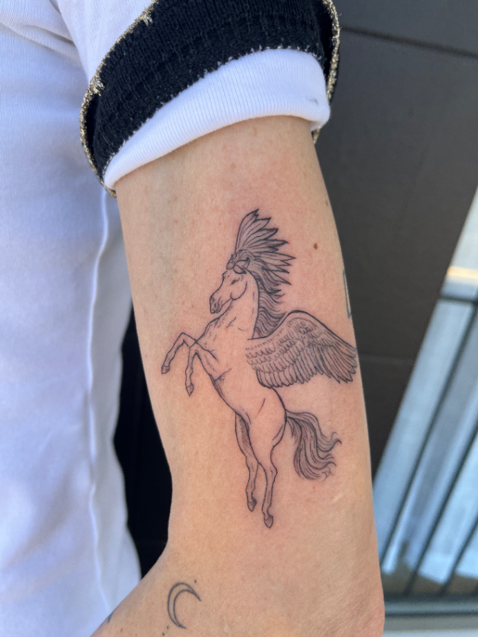 Illustrative pegasus tattoo on forearm in fine-line style.
