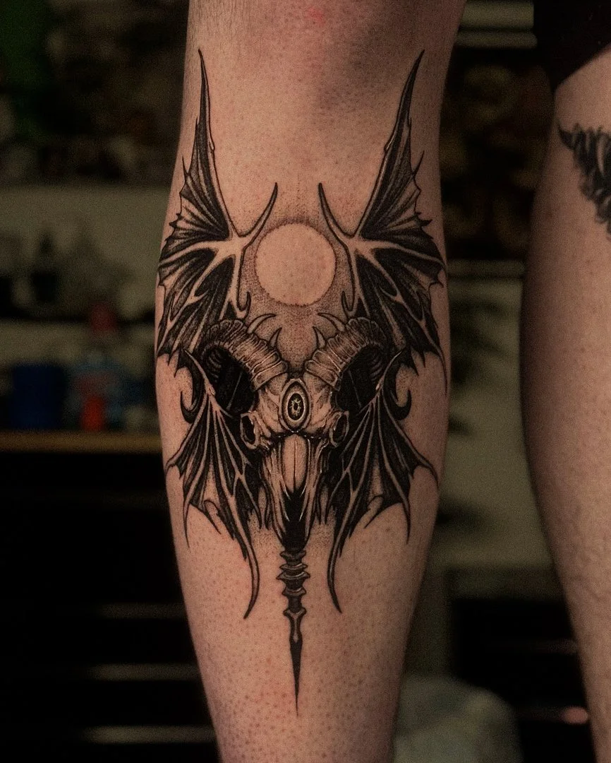 Intricate blackwork tattoo of a skull with bat wings.