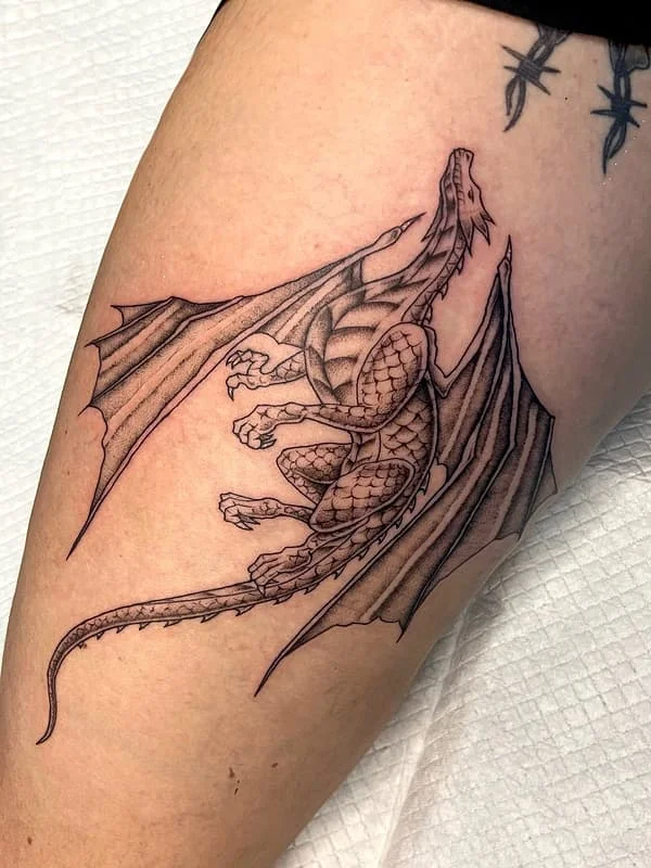 Large blackwork dragon tattoo on thigh, dense coverage style