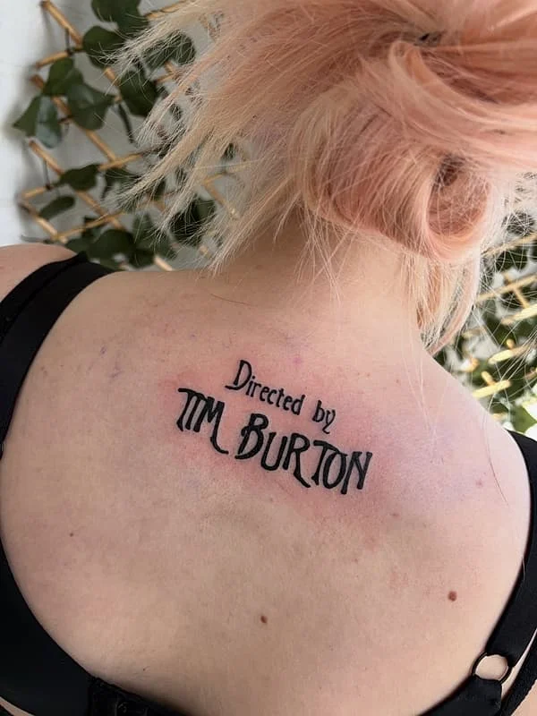 Script tattoo on back reading 'Directed by Tim Burton'.