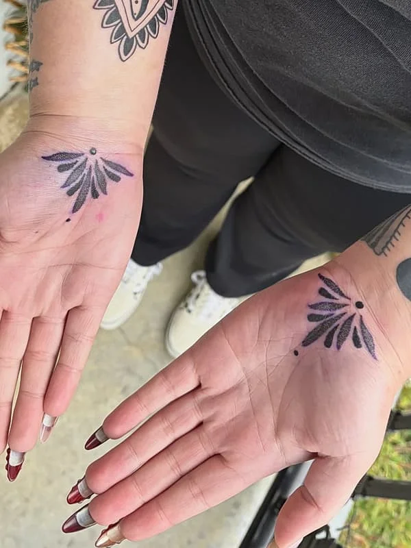 Blackwork floral tattoo on both hands.