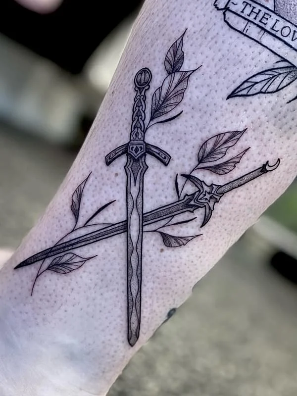Fine-line tattoo of two swords with leaves on forearm.