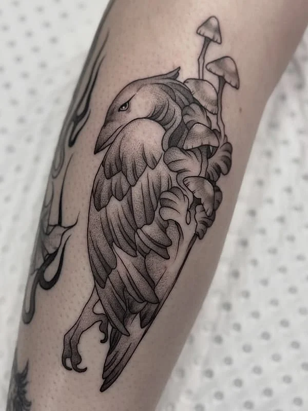 Black-and-grey bird and mushrooms on forearm