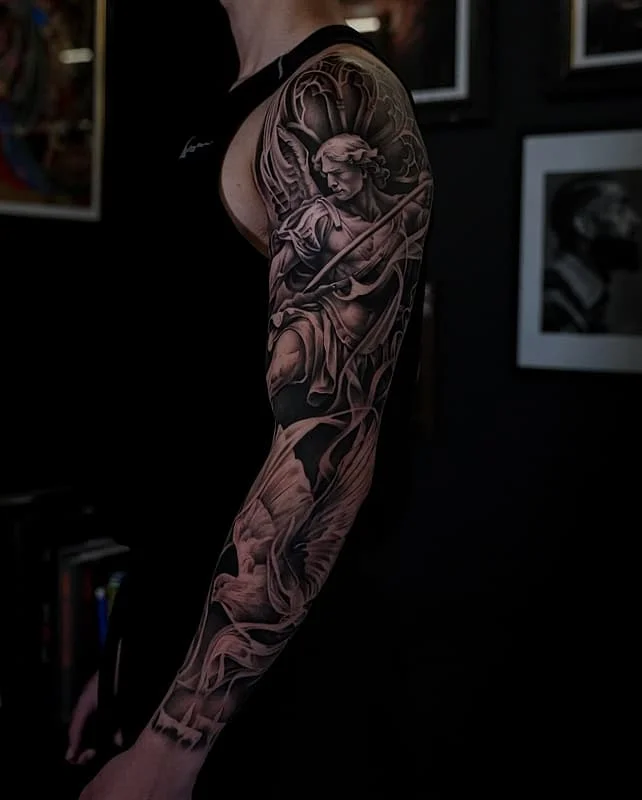 Detailed black-and-grey angel tattoo on a full sleeve.