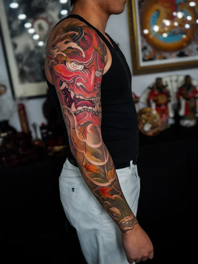 Colorful Japanese full-sleeve tattoo featuring a dragon and mask.