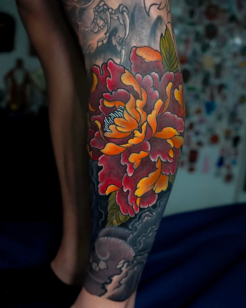 Vibrant peony tattoo on a leg.