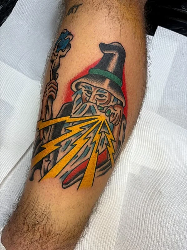 Colorful wizard tattoo with lightning on forearm.