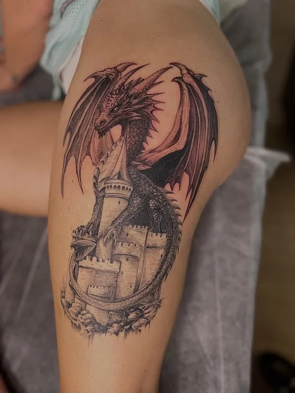 Large black-and-grey dragon tattoo on thigh.