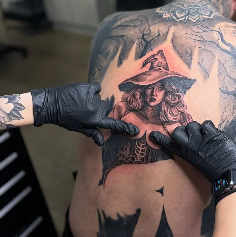 Large back tattoo of a witch in a forest setting.