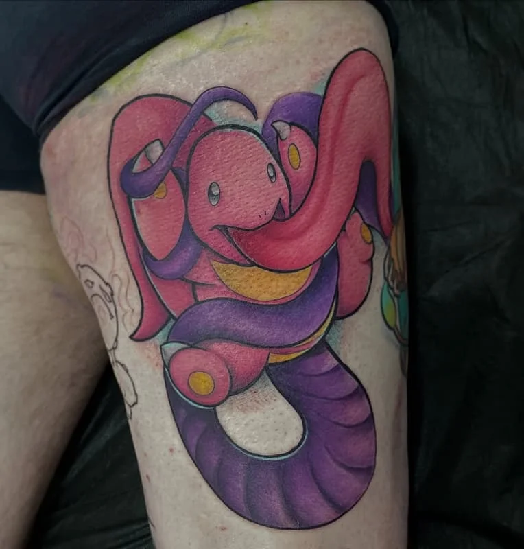 Colorful cartoon snake tattoo on thigh.