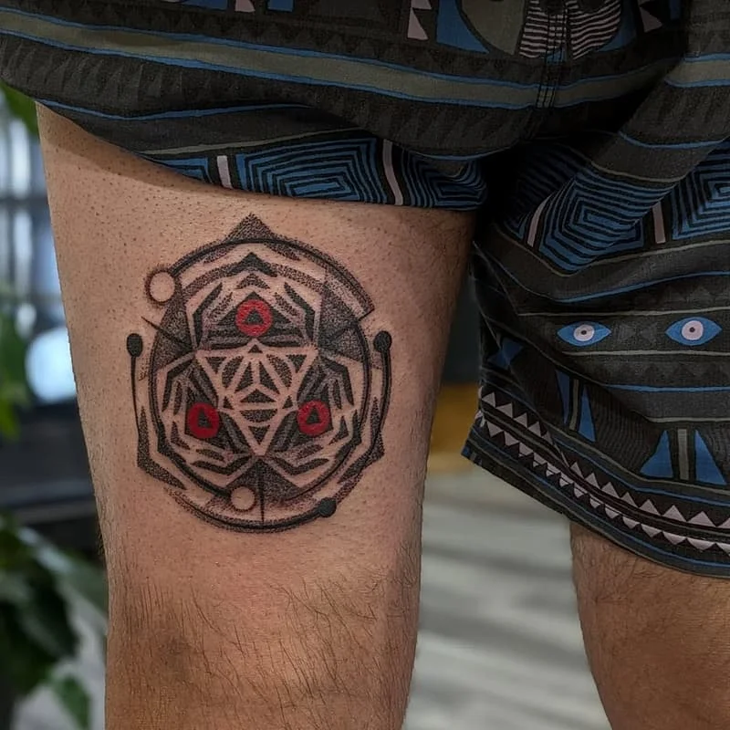 Geometric blackwork tattoo on thigh with sacred symbols.