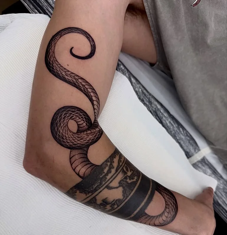Detailed blackwork snake tattoo on the arm.