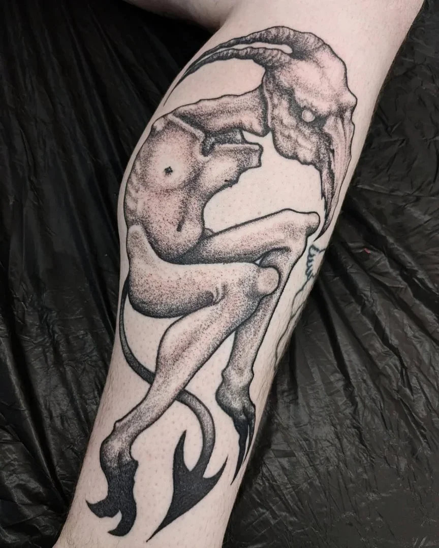 Surreal blackwork tattoo of a demon on a leg.