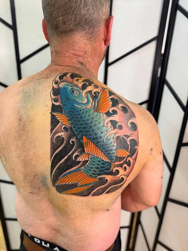 Large colorful koi fish tattoo on a man's back.