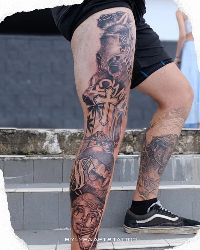 Large black-and-grey leg tattoo featuring various designs.