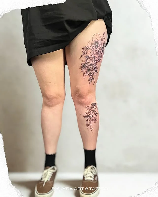 Large fine-line floral tattoo on a woman's thigh.