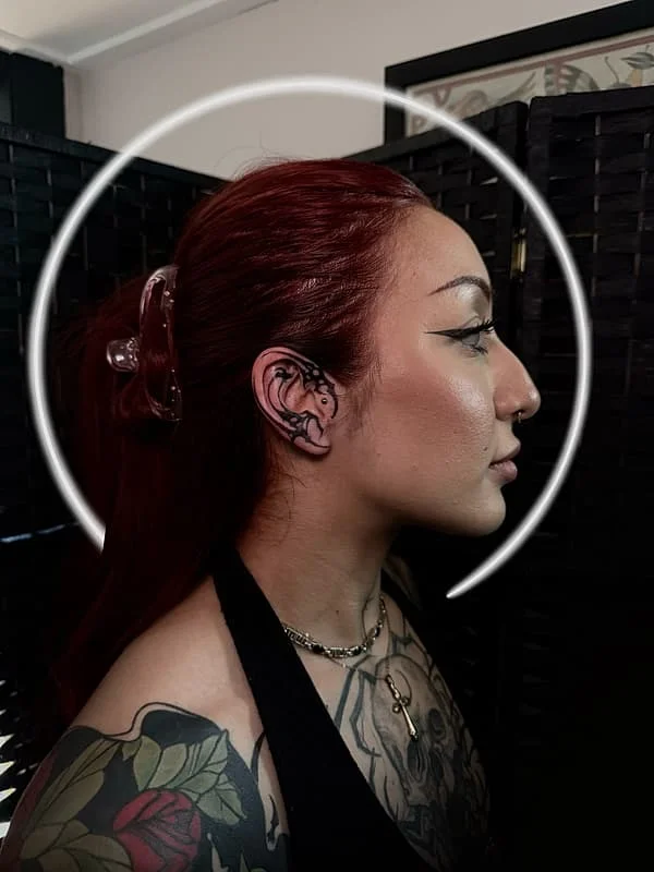 Blackwork floral tattoo behind ear and on arm.
