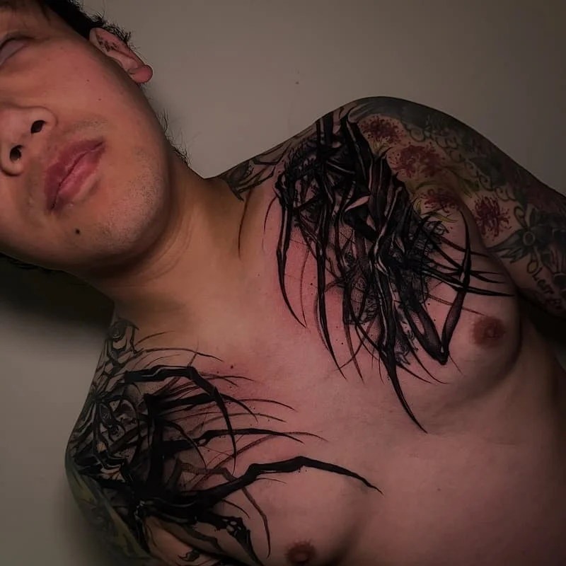 Large blackwork tattoo on chest and shoulder.