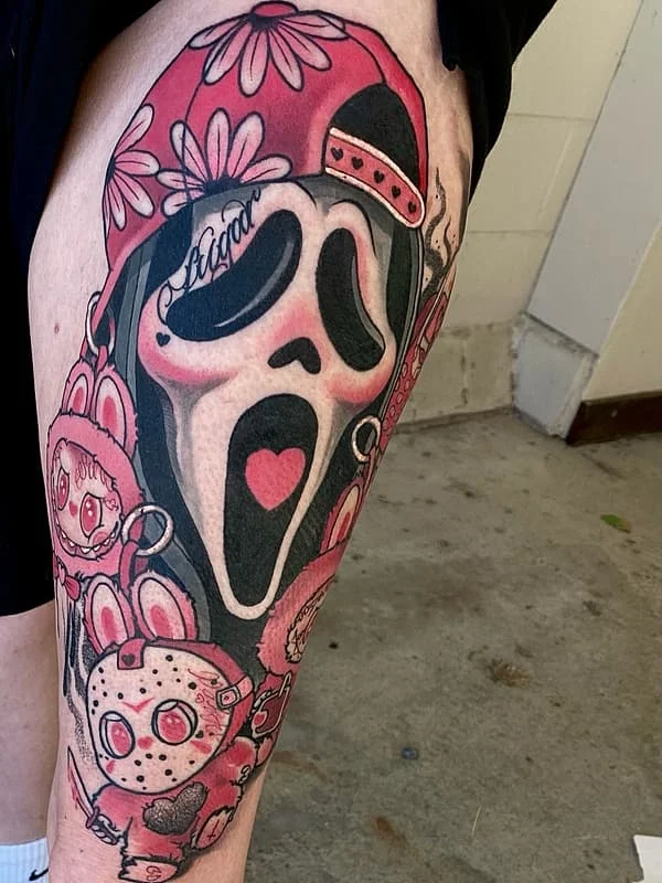 Colorful horror-themed thigh tattoo with skull and cartoon elements.