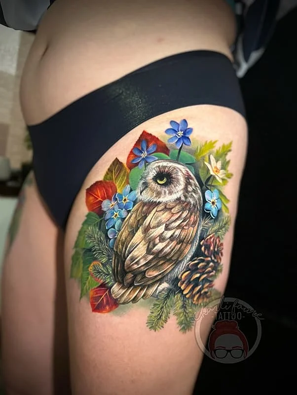 Realistic owl tattoo with flowers on thigh.