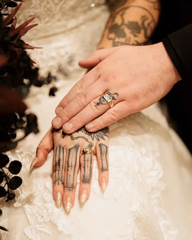 Close-up of blackwork and fine-line tattoos on hands.