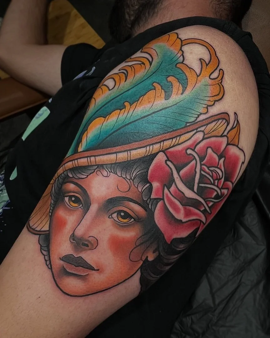Colorful neo-traditional tattoo of a woman's face with a feather and rose.