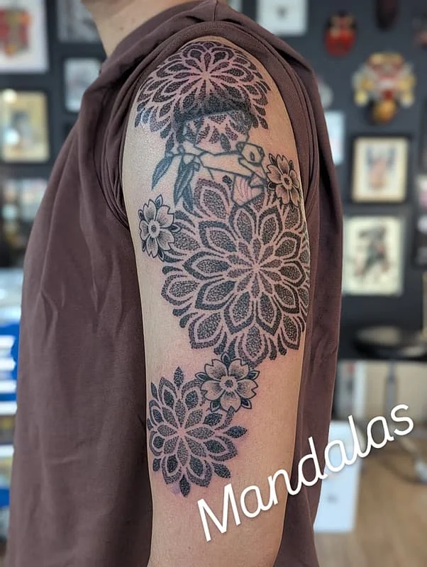 Large mandala tattoo on the arm with floral designs.