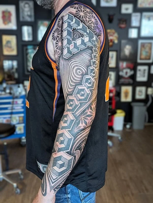 Intricate geometric full-sleeve tattoo on a male arm.