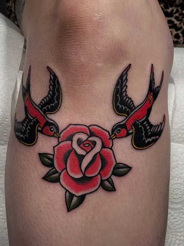 Traditional tattoo of birds and a rose on thigh.