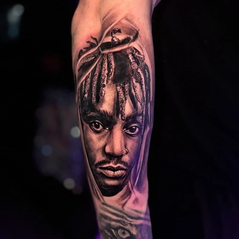 Black-and-grey portrait tattoo on forearm.