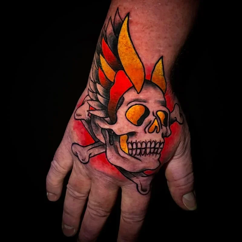 Colorful traditional skull tattoo on a hand.