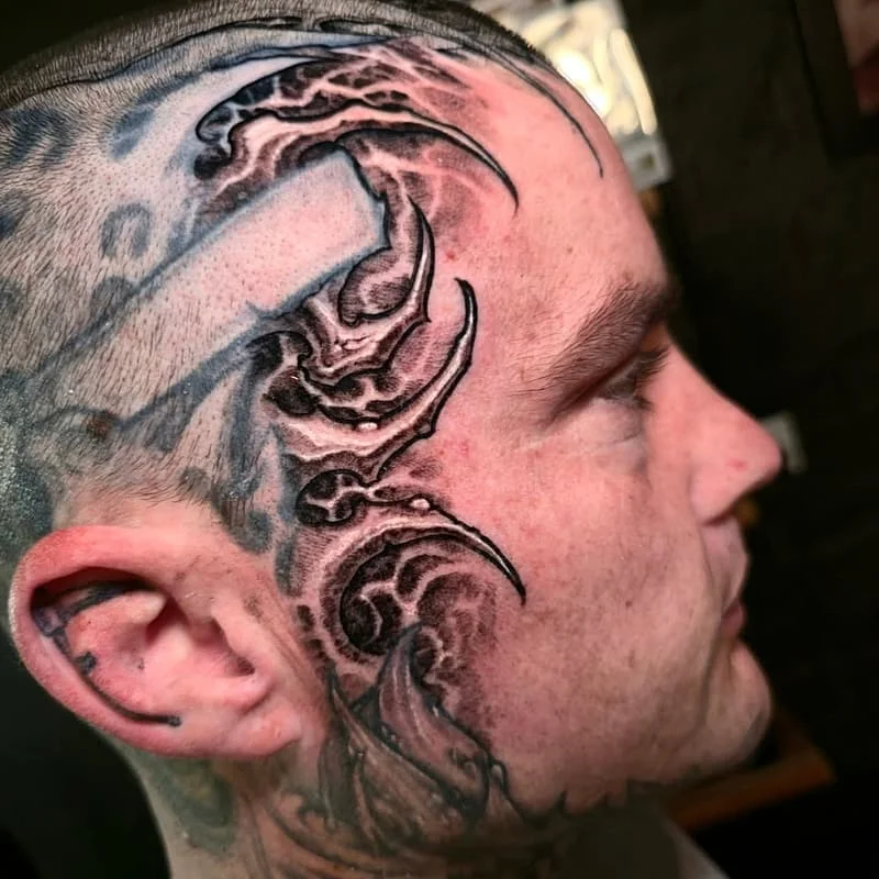 Abstract blackwork tattoo on the side of a man's face.