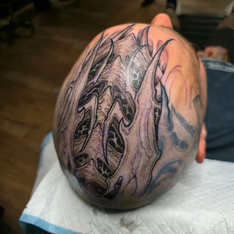Large abstract tattoo design on a shaved head.