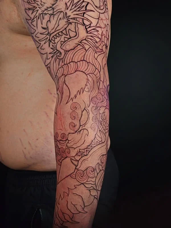Large Japanese dragon tattoo on the arm with waves.