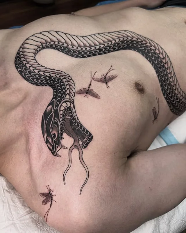 Detailed blackwork snake tattoo on chest and arm
