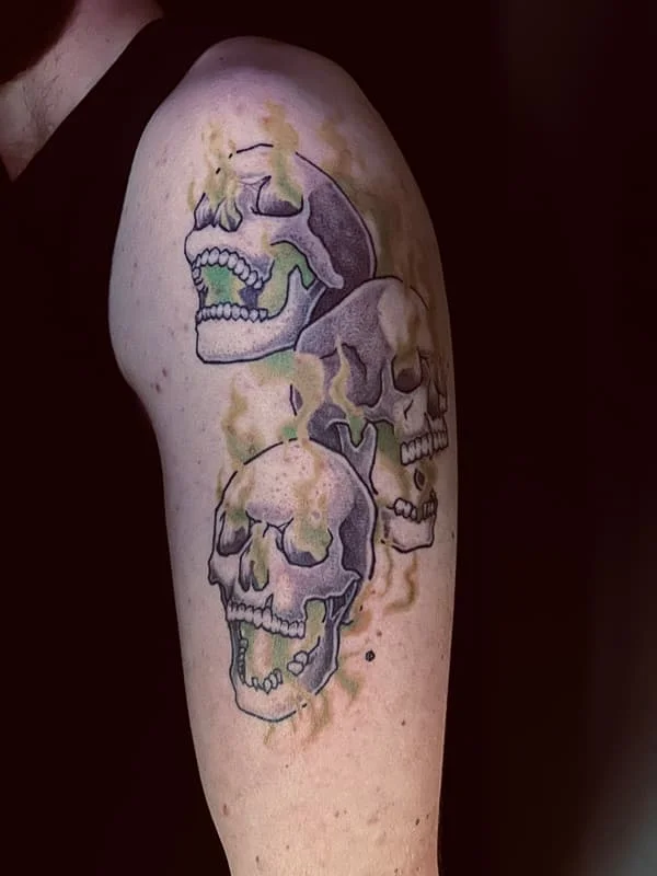 Colorful watercolor skull tattoo on an arm.
