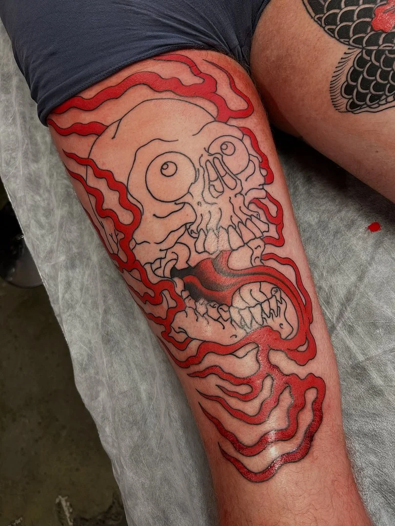 Illustrative skull tattoo with red lines on leg.
