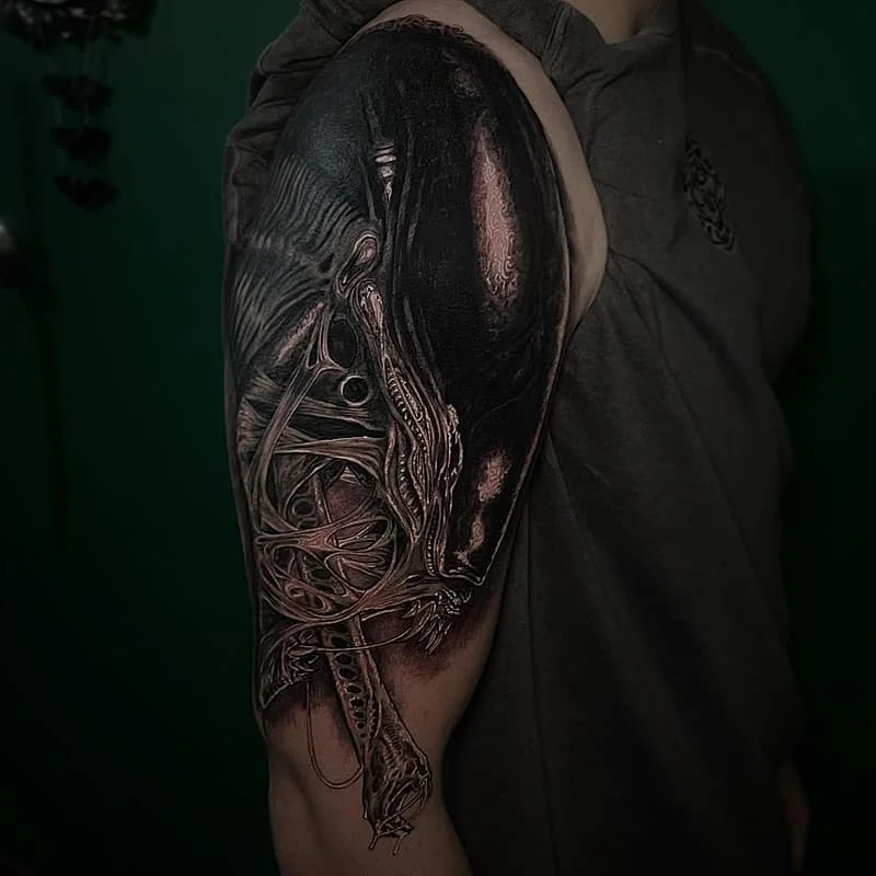 Large black-and-grey biomechanical tattoo on arm.