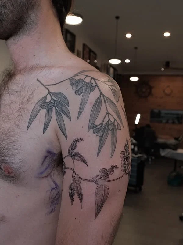 Intricate botanical tattoo on arm and shoulder.