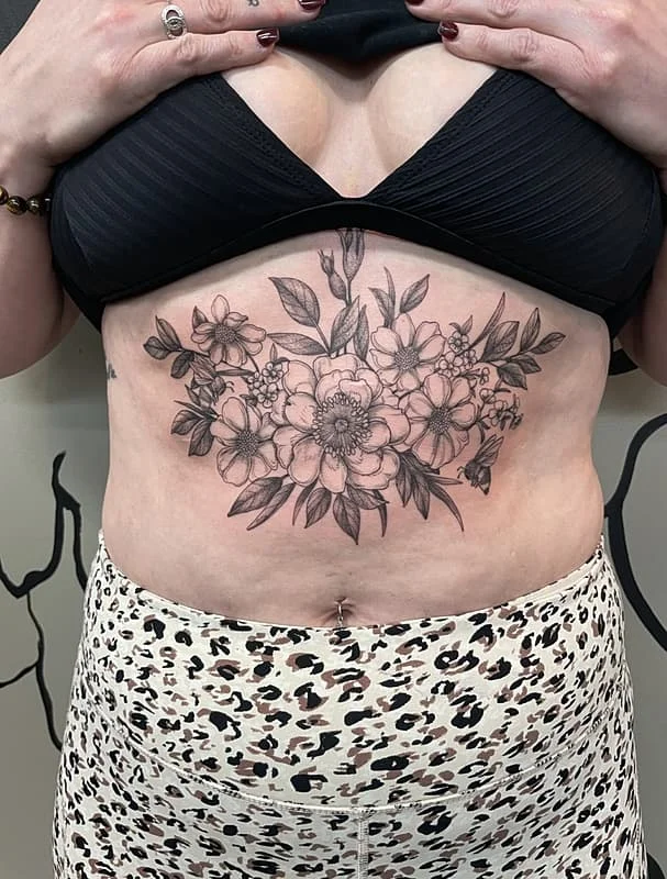 Large blackwork floral tattoo on chest and rib area.