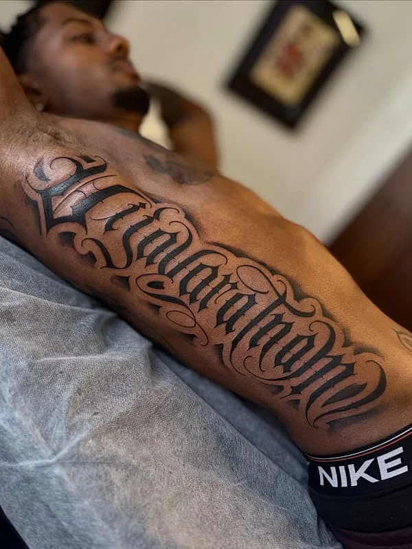 Bold script tattoo on a man's arm.