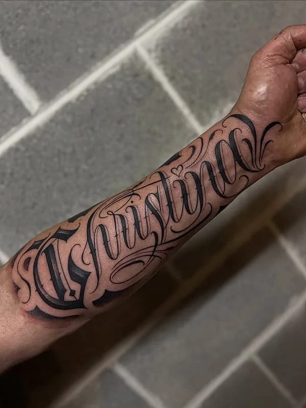 Elegant script tattoo of the name Christina on forearm.