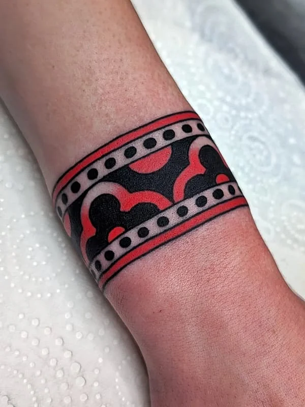 Bold geometric wrist tattoo in black and red.