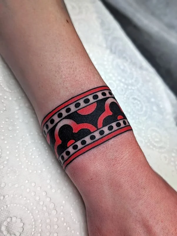Bold geometric wrist tattoo in black and red.