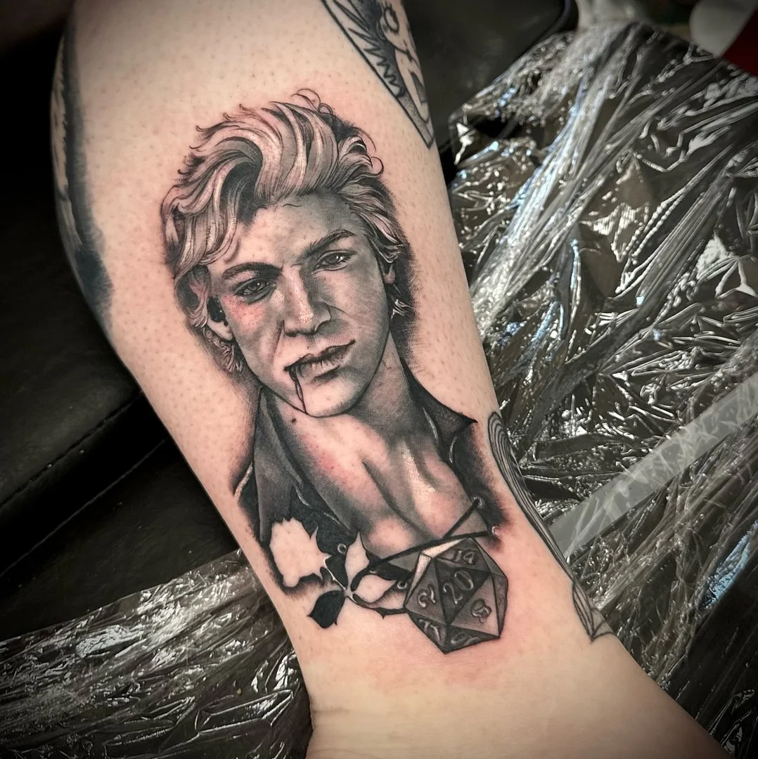 Detailed black-and-grey portrait tattoo on forearm.