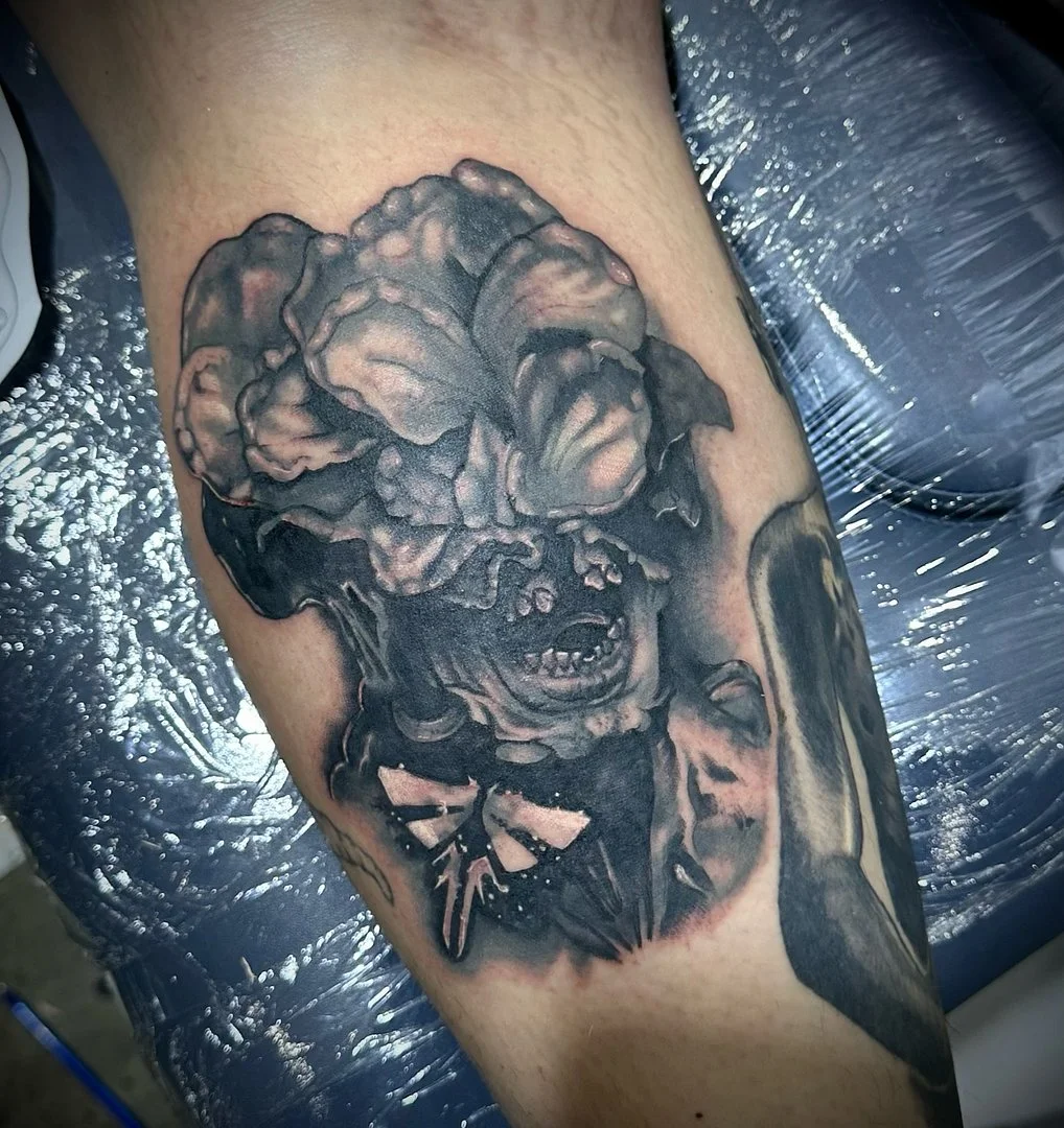 Detailed black-and-grey monster tattoo on forearm.